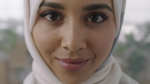 close up portrait of young muslim business woman looking up at camera confident wearing traditional hijab headscarf in office workspace background