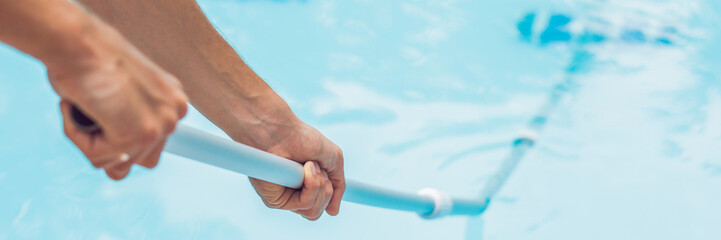 Cleaner of the swimming pool . Man in a blue shirt with cleaning equipment for swimming pools,...