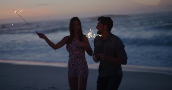 lively young couple waving sparklers dancing celebrating new years eve on calm beach sunset background sparkle firework
