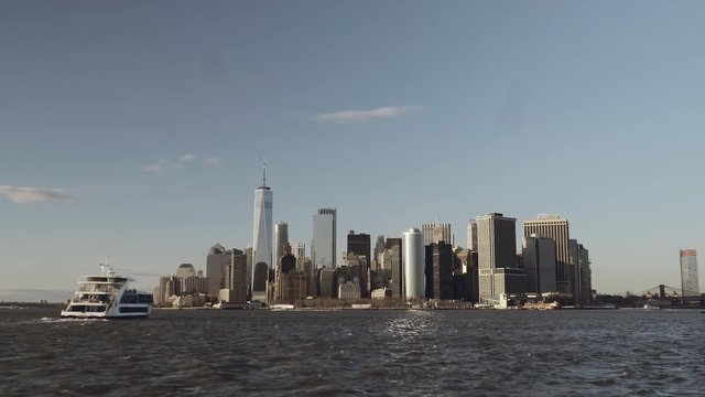A boat approaching financial skyscrapers in downtown New York in Lower Manhattan filmed from the river in late afternoon