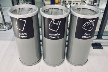 Three grey separate plastic container, which are recycling symbols stamped on paper, plastics, and other materials in front, trash in department store, 3 kinds of recycle bin.