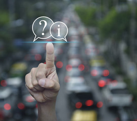 Businessman pressing question mark and information chat icon over blur of rush hour with cars and...