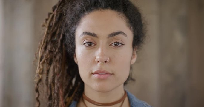close up portrait of beautiful young mixed race woman looking calm pensive female dreadlocks hairstyle real people series
