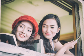 Asian women traveler have reading a book and talking in the train with happiness at Hua Lamphong station at Bangkok, Thailand.