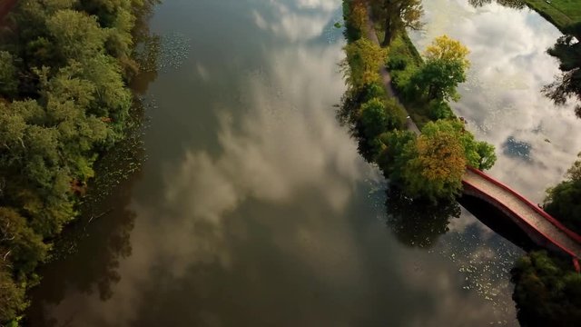 Public park romantic small walking bridge over pond located at green quiet scenery trees hanging over both sides of the walk way beautiful place to be enjoying the outside 4k high resolution