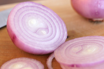 Red onion slices on wooden cutting board