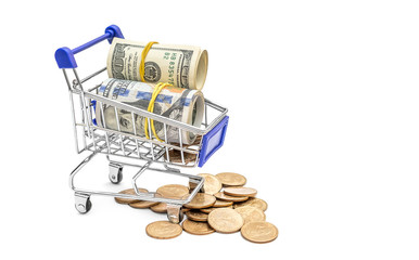 Shopping cart with dollar bills and coins on white.