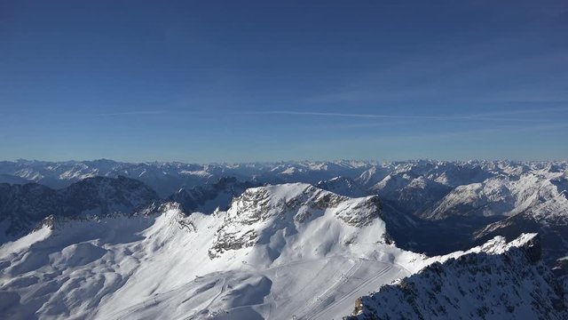 Zoom out of the alpine panorama seen from the summit of Germany's tallest mountain, the Zugspitze, looking southwest including the skiing resort on the Zugspitz glaciers, shot on a beautiful winter's 