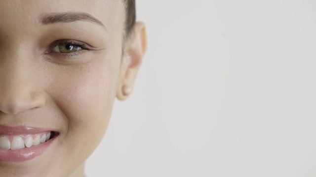 close up beautiful hispanic woman half face smiling happy wearing earings makeup cosmetics on white background
