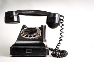 Old black telephone on white