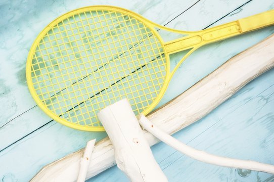 Yellow plastic badminton racket on a blue wood background