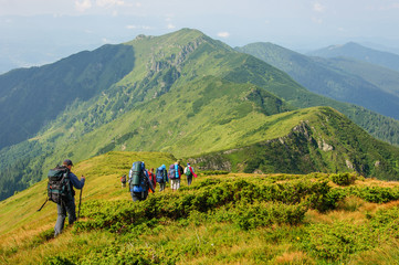 Group of tourists with large backpacks are on mountain