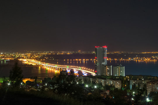 Moon eclipse. View of the night city of Saratov, Russia. The lights of a metropolis in the night. View of the bridge over the Volga River.