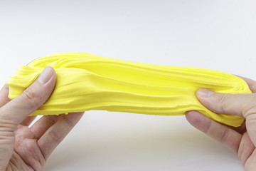 Hands Stretching Yellow Modeling Clay on White Background