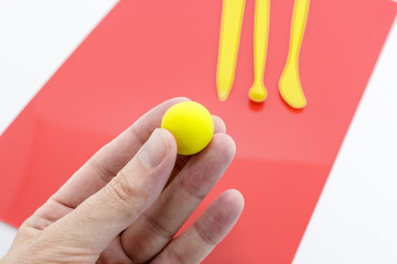 Hand Holding a Ball of Yellow Soft Clay