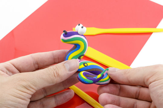 Hands Crafting a Colorful Snake Out of Modeling Clay