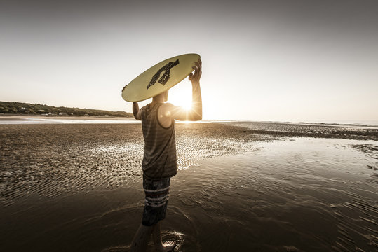 Surfer at beach against sun