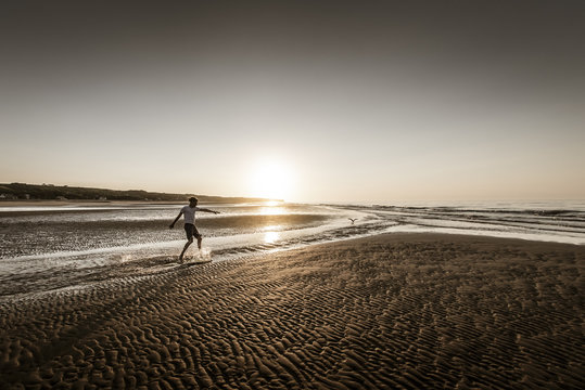 surfing at the beach against sunset