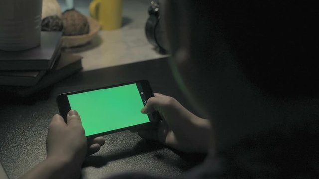 Over The Shoulder Shot Of A Boy Using Smartphone With A Key-green Screen.