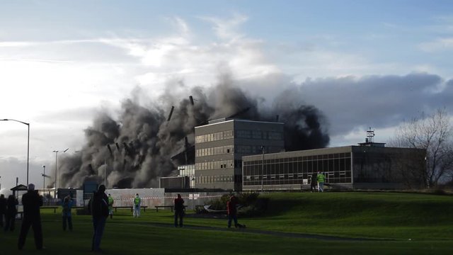 Abandon derelict industrial building is imploded in a controlled demolition on a sunny summer day
