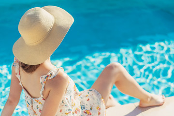 Summertime in pool. Young woman with floppy hat and at pool.