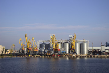 Naklejka premium Cranes and granaries, cisterns with wheat in the port in clear weather, the sea.