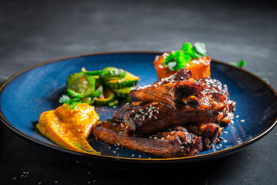 Tasty roasted ribs with sesame and vegetables on blue plate