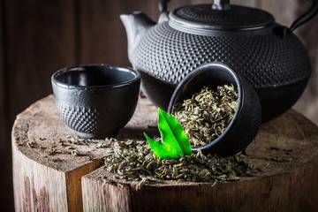 Closeup of fresh green tea with iron teapot and cup