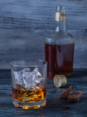 a bottle and a glass of whiskey and ice and chocolate