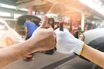 Mechanic hand checking and fixing a broken car in  garage.hand of mechanic with thumbs up and tool