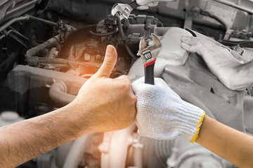 Mechanic hand checking and fixing a broken car in  garage.hand of mechanic with thumbs up and tool