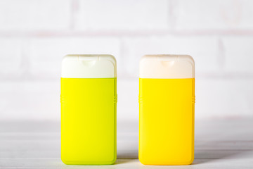 Two closed plastic shampoo and conditioner containers, green and yellow, on white background. Copy space