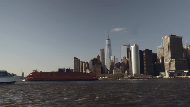 Taxi boat passing by financial skyscrapers in downtown New York in Lower Manhattan filmed from the river in late afternoon