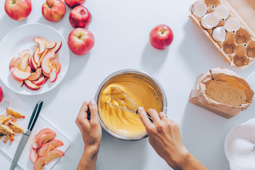 Top view of female hands holding whisk and mixing bowl