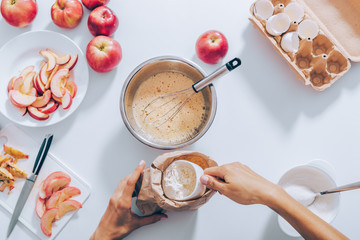 Woman measuring flour for dough to prepare apple pie