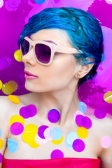 Portrait of young pretty female girl adult woman fashion luxury sexy model with blue hair relaxing wearing pink sunglsses in bath isolated by pink water with colorful confetti. Skin and beauty care