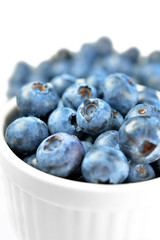 Fresh colorful Bilberries blueberries in white bowl isolated on white background. Selective focus