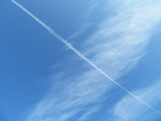 Fototapeta na wymiar Blue sky with white cirrus clouds and airplane jet trail. Cloudscape as beautiful weather background