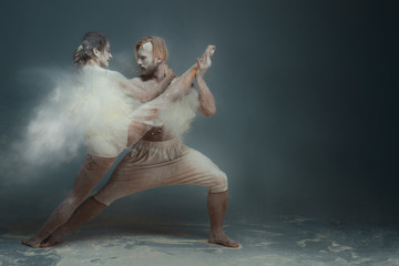 Dancing in flour concept. Girl woman female and muscle fitness guy man male couple in love and in...