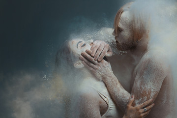 Dancing in flour concept. Guy man male shuts mouth of girl woman female. Couple in love and in relationship making dance element prefomance in flour / white dust on isolated black / grey background