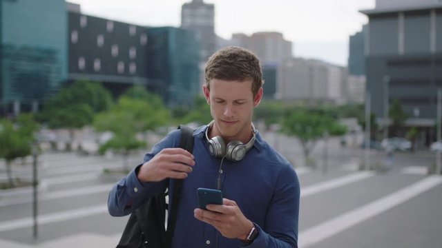 Portrait Of Attractive Young Man Student Texting Browsing Social Media Using Smartphone App On College Campus Enjoying Urban Lifestyle