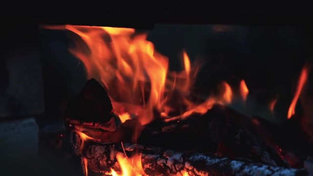 Charred wood in the fire. Burning wood in bright flames in the dark, close up, dynamic scene, toned video, 50fps