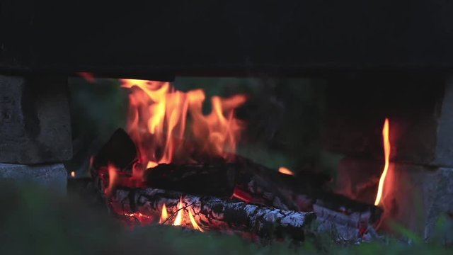 Charred wood in the fire. Burning wood in bright flames in the dark, close up, dynamic scene, toned video, 50fps