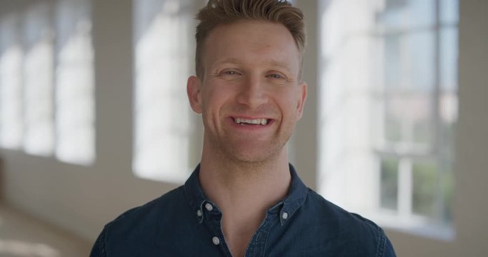 portrait of successful young man smiling cheerful looking at camera enjoying lifestyle satisfaction success handsome caucasian male windows background real people series