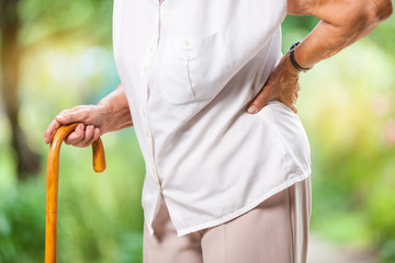 Elderly woman outdoors with back pain