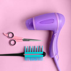 Hairdressing tools poster Scissors, hair dryer and flat comb are lying on pink background Flat lay...