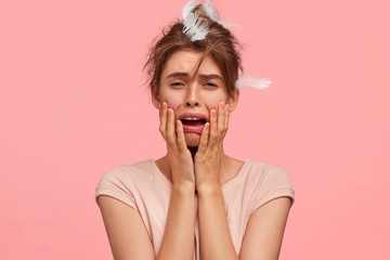Studio shot of desperate female cries desperately, has miserable expression, feels fed up of...