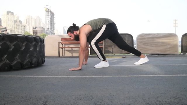 Strong Arab male exercising doing Plyo pushups and tire flips 