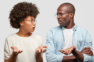 Confused African American couple look at each other angrily, clasp hands, don`t know where their...