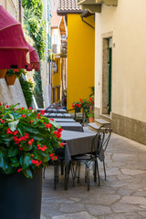 tables, chairs and flowers in the small alley of Varenna